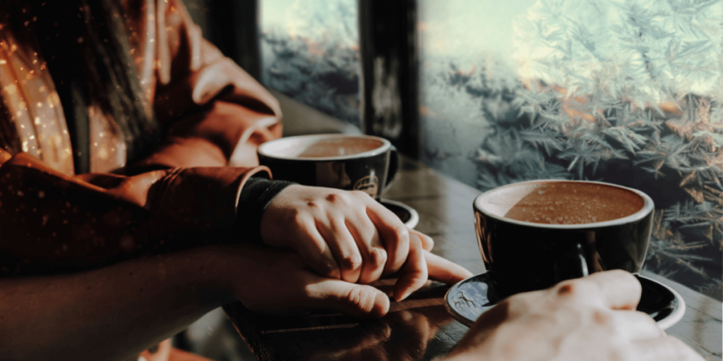 two people holding hands over coffee during hard times