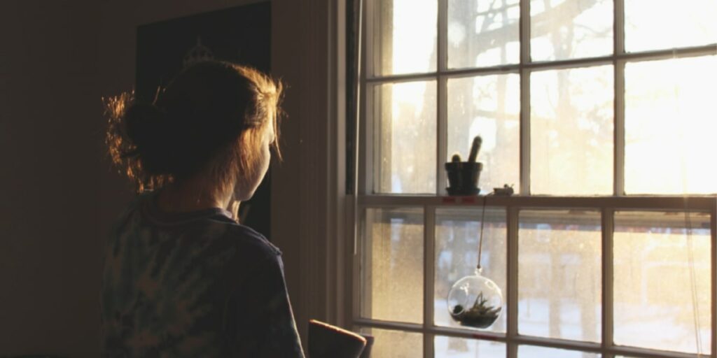 girl looking out window longingly