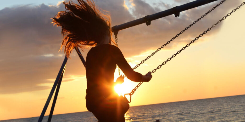 girl swinging with the sun shining behind her