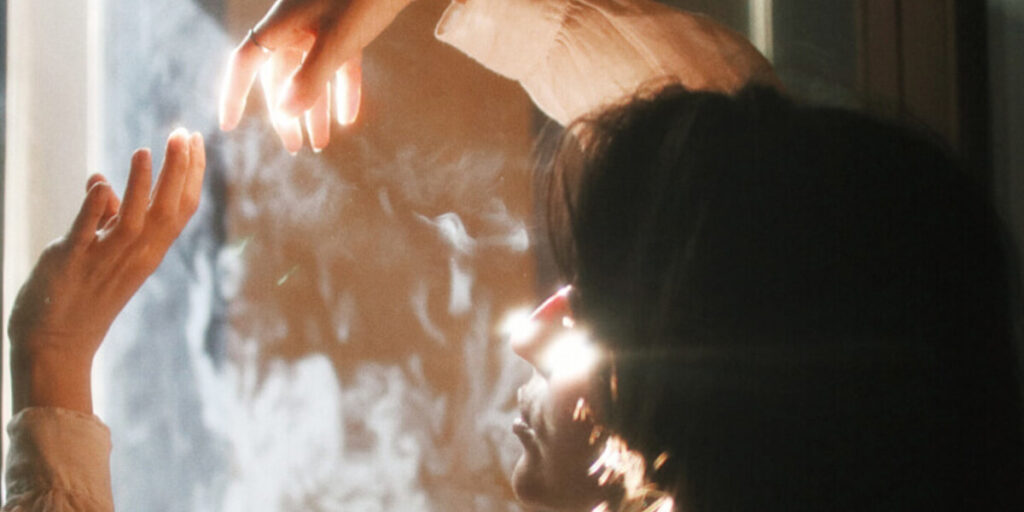 woman interacts with glimmers of light through her window, suicidal ideation and ketamine assisted therapy